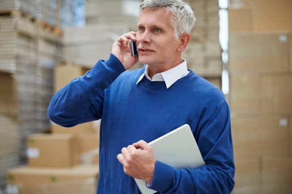 Unternehmer mit Handy im Lager {{brizy_dc_image_alt imageSrc=